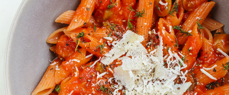 A bowl of pasta topped with tomatoes and parmesan.