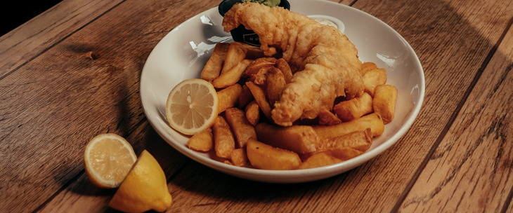 Fish and chips with lemon wedges on a wooden table.