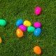 Colorful plastic easter eggs scattered on green grass.