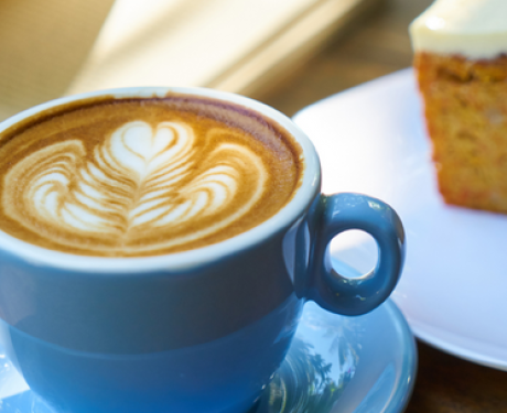 A cup of coffee and a slice of cake on a table.