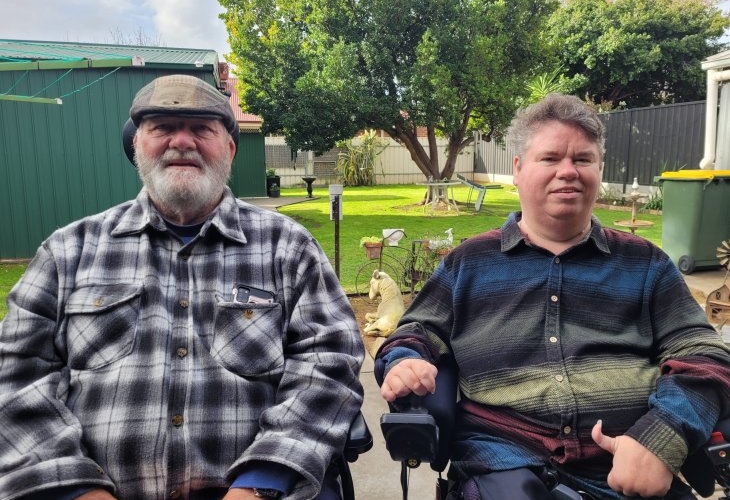 Two men in wheelchairs sitting in a backyard.